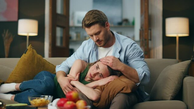 Gentle man regretting woman crying at sofa. Calm guy comforting beloved lady