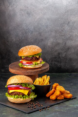 Mouth-watering delicious sandwiches fries chicken nuggets on black board fries pepper on dark gray blurred background