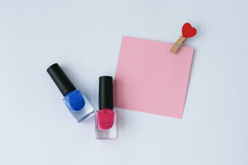 Colorful nail polish bottles and paper note on a white background.