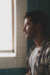 Fashionable bearded young man with tattoos in natural window light 