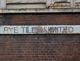 Old street sign on a brick wall with some text
