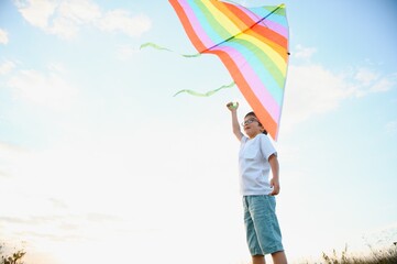 Children launch a kite in the field at sunset.