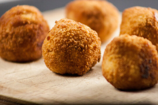 Classic Spanish croquettes on wooden board with dim light in the background. Fried potato