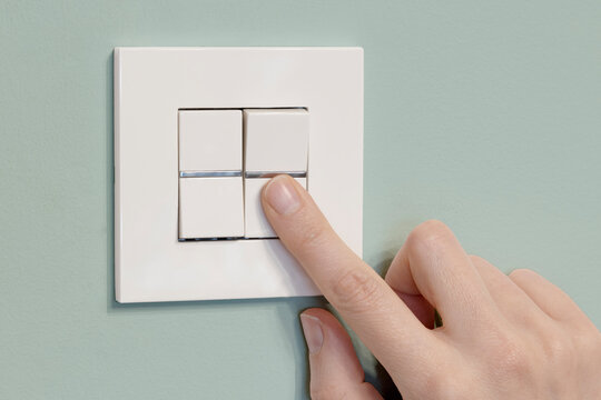 dedo pulsando el interruptor de la luz sobre fondo verde