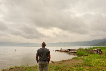 African American man tourist looking out over the still waters of Lake Bosumtwi, Ghana