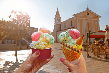 Couple with beautiful bright sweet ice cream of different flavors in the hand.Background of   view of the see and old street  in  Porec .Porec is a tourist destination on Adriatic coast of Croatia - 594759089