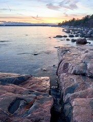 Obraz premium Stunning coastal shoreline, featuring a rocky shore and tranquil waters, with orange sunset