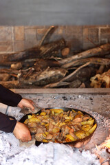 Unrecognizable person preparing meat and potatoes under the iron bell ('peka') in the fireplace. Traditional rural meal in Croatia. Selective focus.
