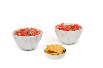 2 identical bowls containing freshly made salsa with a bowl of tortilla chips