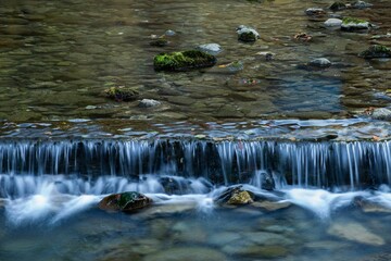 Close-up shot of a small cascading waterfall in the pond with small rocks.
