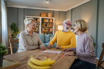 Group of people senior man and women play leisure board game at home