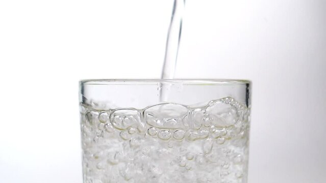 Sparkling water slowly pouring into a glass
