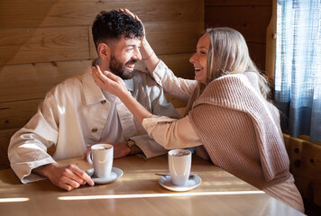 A young couple sits at a table in a cafe and enjoys chatting in the sunlight