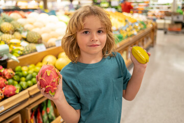 Fototapeta premium Kid with fruits. Kid choosing food in grocery store or a supermarket. Fruit and vegetable.