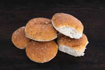 Six Brown Oatmeal Baps or Rolls on a dark wooden oak table