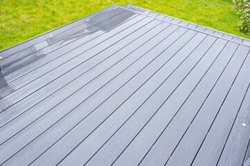 Ash grey composite decking on a rainy wet day showing the full grain of the decking boards A good...