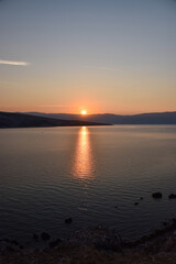 Vibrant sunset descending on the horizon, sea in golden colors, small waves gently touching the...