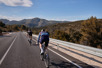 Two professional cyclists are riding.Men in full cycling gear are training on a mountainous road in Spain, surrounded by breathtaking views.Alicante region