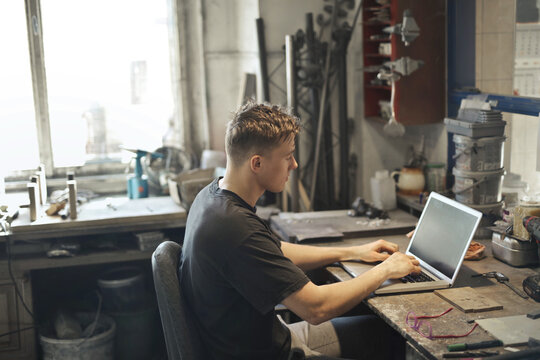 young man in his workshop uses a computer