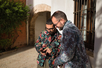 Real marriage of gay couple, with travel suitcases, checking hotel location on their cell phone. Concept lgtb, lgtbiq+, couples, in love, travel, apps.