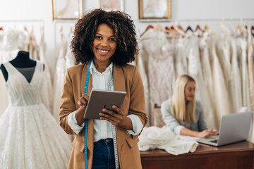 A beautiful wedding dress designer holds a tablet and looks at the camera