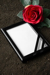 above view of picture frame with red flower on dark soil grim reaper death funeral portrait