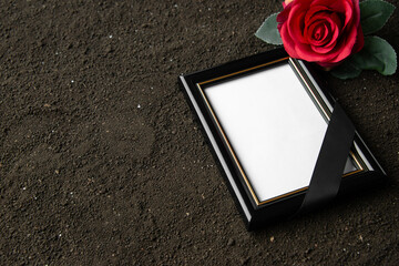 front view of picture frame with red flower on dark soil grim reaper funeral portrait death