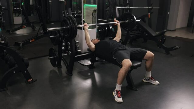 Professional Athlete, Bench Press, Hardcore Gym. Bodybuilder is utilizing weight machines to target his arms, and is also focusing on barbell bench presses.