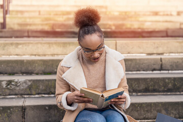 Obraz premium woman student reading a book, making a plan on stairs in city concept of studying hard Lifestyle photo