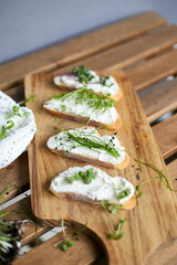 Variety of sandwiches for breakfast with slice of whole grain bread, cream cheese, mixed microgreens garnished on wooden table Top view Flat lay