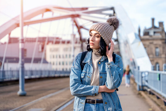 a young woman in a denim jacket is talking on the phone and waiting for a tram at the stop Lifestyle photo