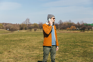 a man with a beard in a gray cap, velvet jacket, holds a smartphone in his hands and speaks on the phone