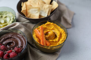 Savory Roasted Carrot Hummus, Spinach Hummus, and Sweet Chocolate Hummus with Raspberries in Dishes