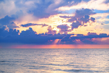 Sunset on tropical beach sea ocean with sunrise clouds. Banner for travel vacation. Scenery sky and reflection rays in water. Dusk, twilight on sea. Tranquil, golden sky background.