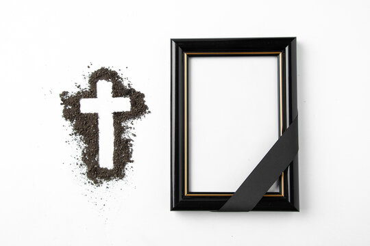 top view of cross shape with picture frame on white surface soil funeral death grim reaper