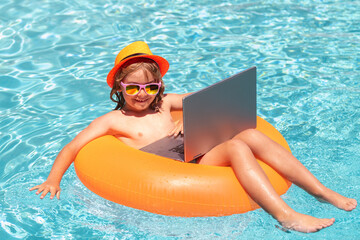 Work outside concept. Child with laptop in swimming pool in summer day.