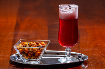 Glass of Belgian fruity red sour cherry kriek beer and party mix nuts, pairing of food and beer in Belgium
