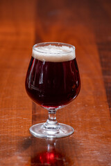 Glass of Belgian abbey red brown beer on table