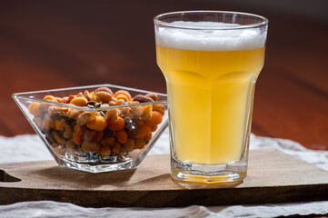 Glass of Belgian white unfiltered beer with notes of coriander and orange peer and different snack nuts