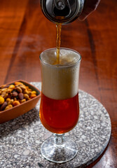 Glass of Belgian light blond beer made in abbey and bowl with party mix nuts