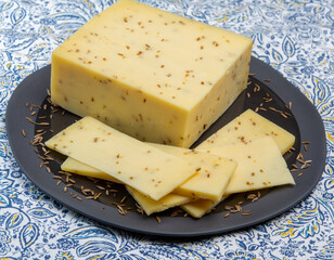 Cheese collection, piece of cow milk Dutch gouda cheese with dried aromatic cumin seeds close up