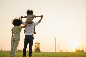 African american family in the community with wind generators turbines, Wind turbines are alternative electricity sources, the concept of sustainable resources and Renewable energy. sunset.