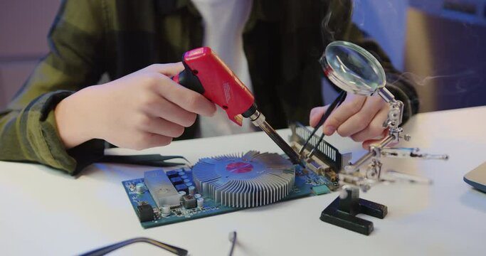 Close Up. Unknown male hands soldering using soldering iron and screwdriwer on the table at hom. Engineer soldering microcircuit.