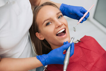 Close-up of female patient having her teeth examined by specialist in dental clinic.