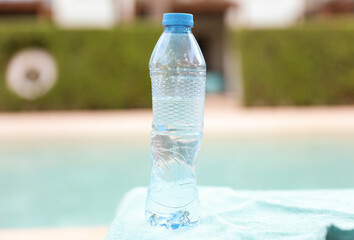 plastic bottles scattered around the pool and beach represent the negative impact of human activity on the environment. The pollution caused by single-use plastic bottles affects the ocean