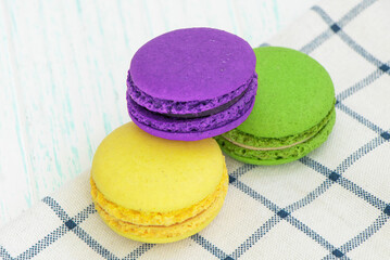 multicolored macaroon cakes on a checkered napkin. red, green, yellow macaroons. Sweet macarons on wooden background. space for text. High quality photo