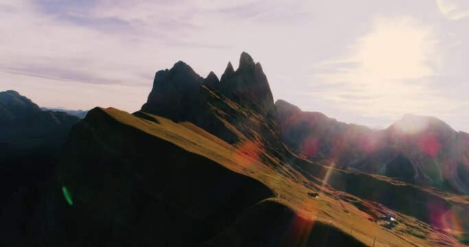 Aerial View. Young man in sport trail clothes stretching on Seceda mountain peak at sunrise. Puez Odle, Trentino, Dolomites, Italy.