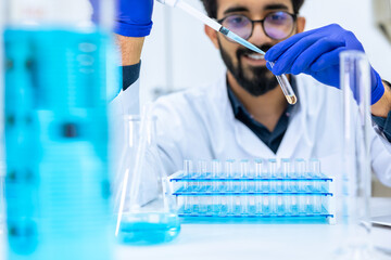 Scientist man testing chemical sample in flask at laboratory with lab glassware.