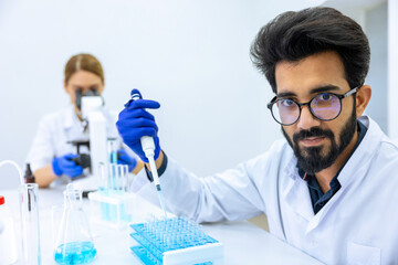 Fototapeta premium Team of scientists examining sample, using microscope and chemical liquids in flask in modern lab