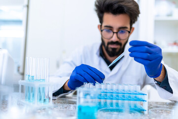 Scientist man testing chemical sample in flask at laboratory with lab glassware.